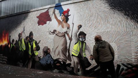 a woman inspects a new mural by the artist pascal boyart aka pboy to pay homage to the yellow vests movement and containing 0 26btc 1000 on a wall in 